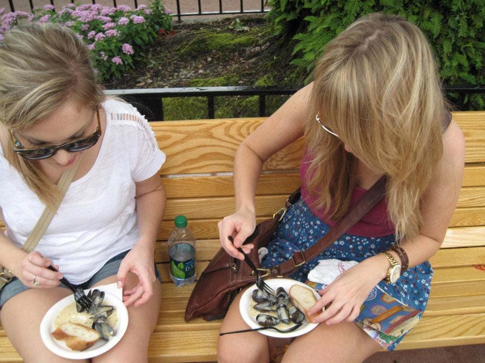Two women eating mussels on a park bench at Disney World
