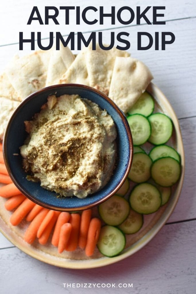 A plate of vegetables and pita bread surrounding a bowl of hummus