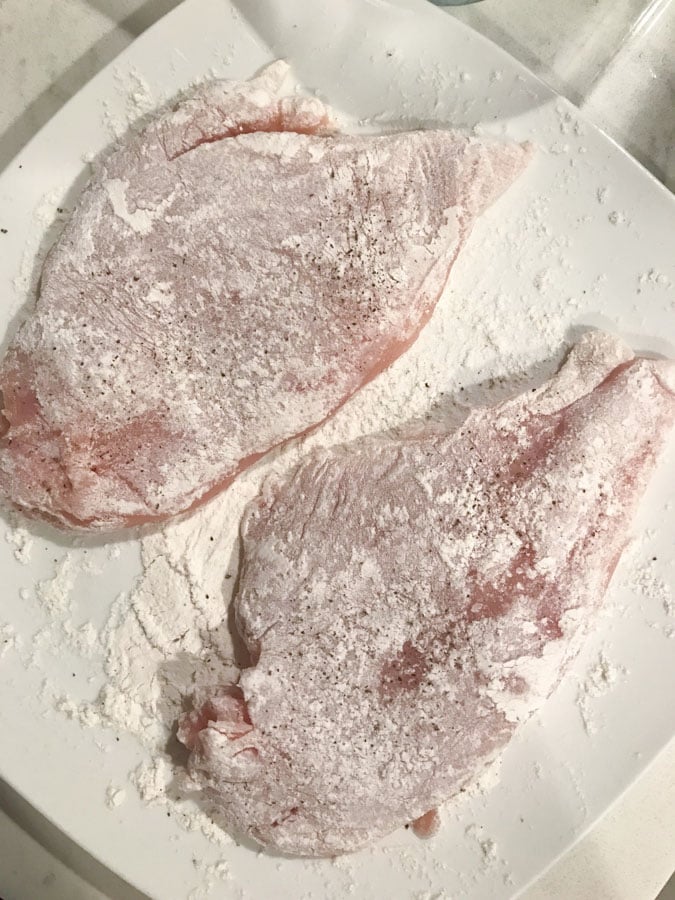 chicken dredged in flour on a white plate