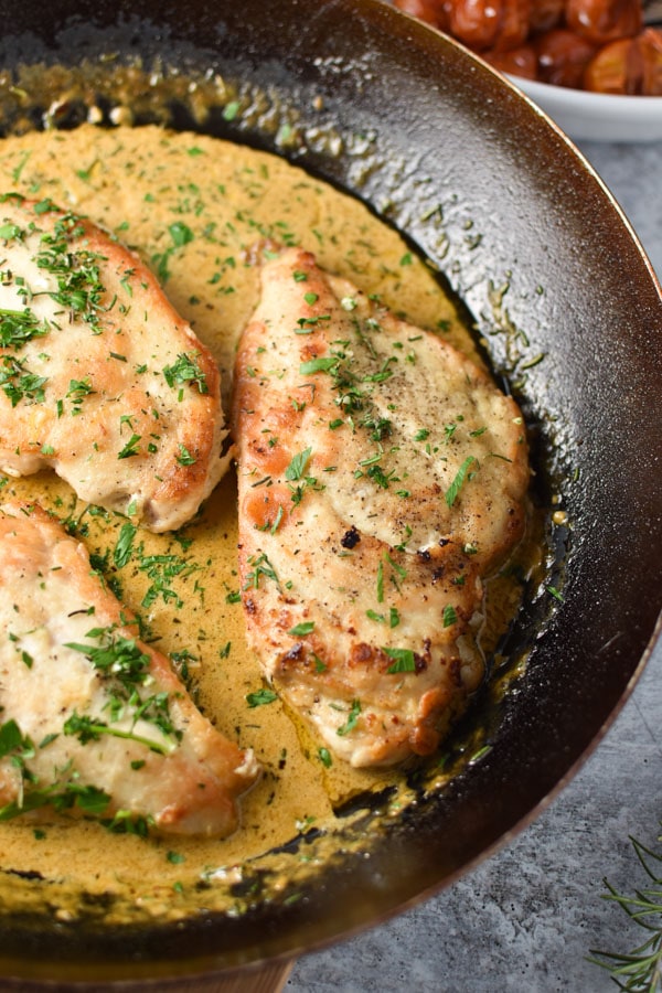 chicken breasts in a black pan with a cream sauce