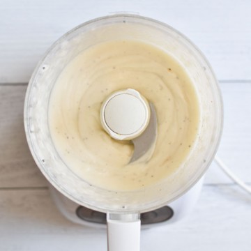 Whipped mayo in a food processor on a white board