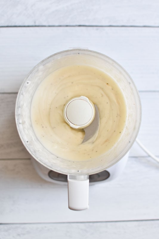 Whipped mayo in a food processor on a white board