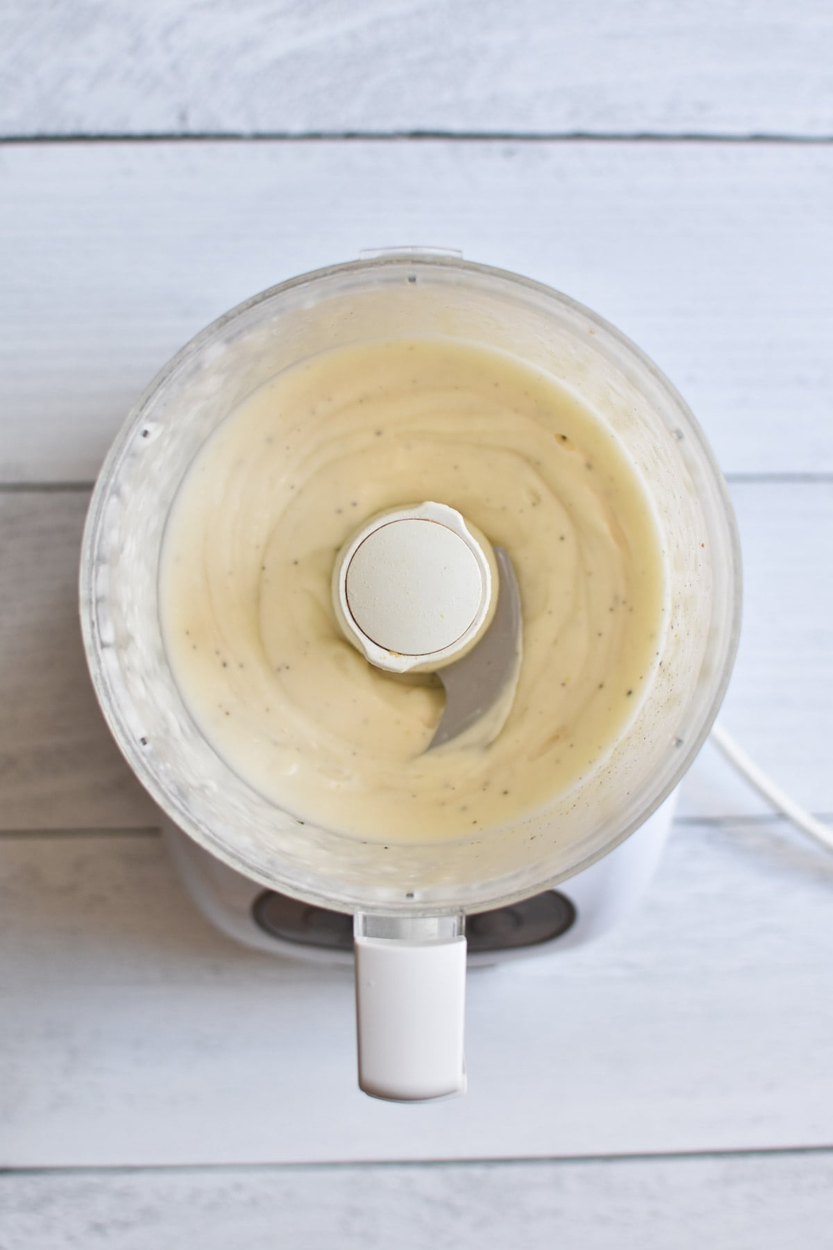 A food processor blending an eggless mayo till smooth.