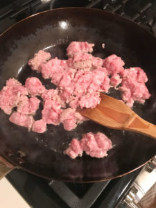 raw meat being browned in a pan