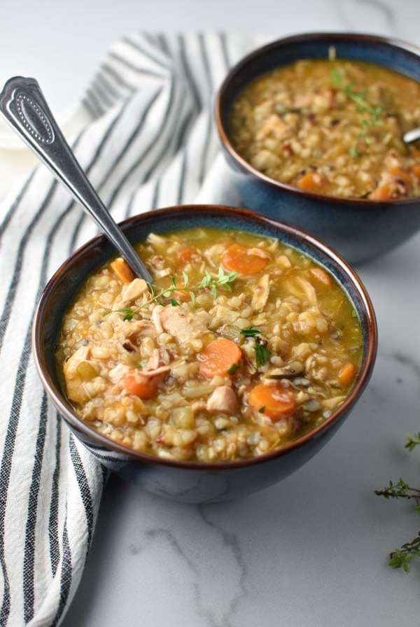 two blue bowls of chicken and rice soup with spoons