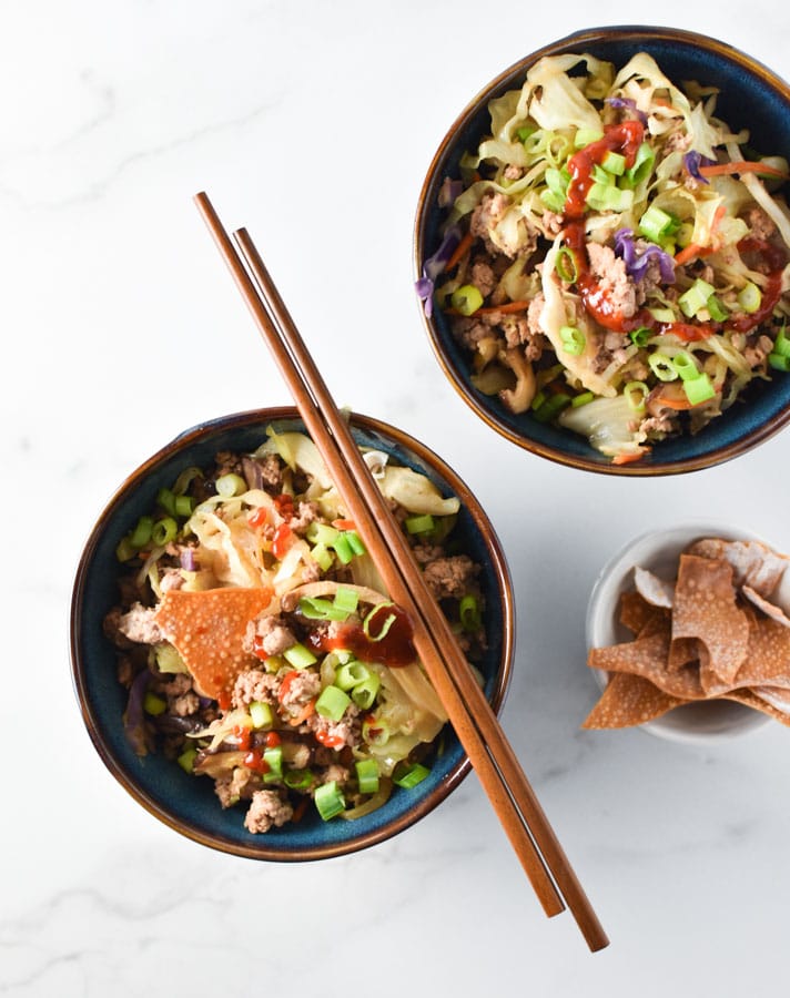 egg roll bowls with chopsticks laying on top and wontons off to the side