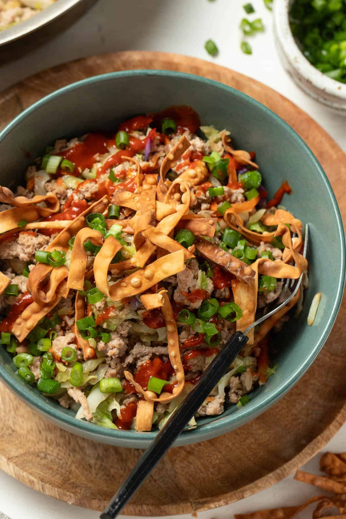 Ground turkey, crisp egg roll chips, green onion and sriracha all mixed together in a bowl.