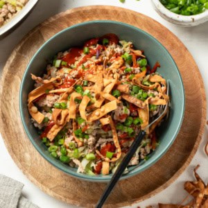 A ground turkey egg roll bowl with a fork and green onions on top.