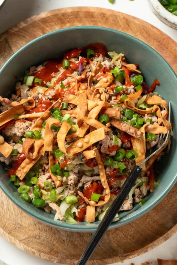 A ground turkey egg roll bowl with a fork and green onions on top.