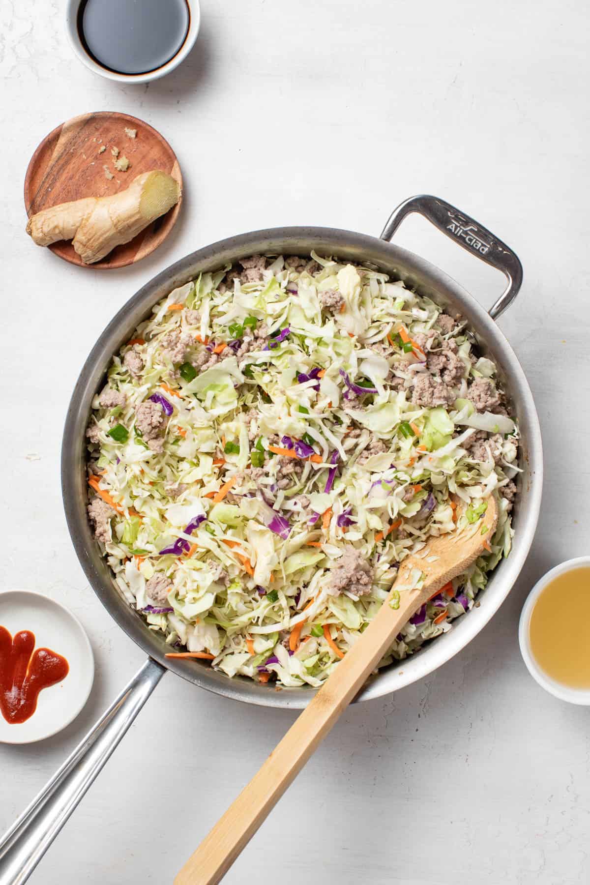 Cooking down the coleslaw mix till it is softened.