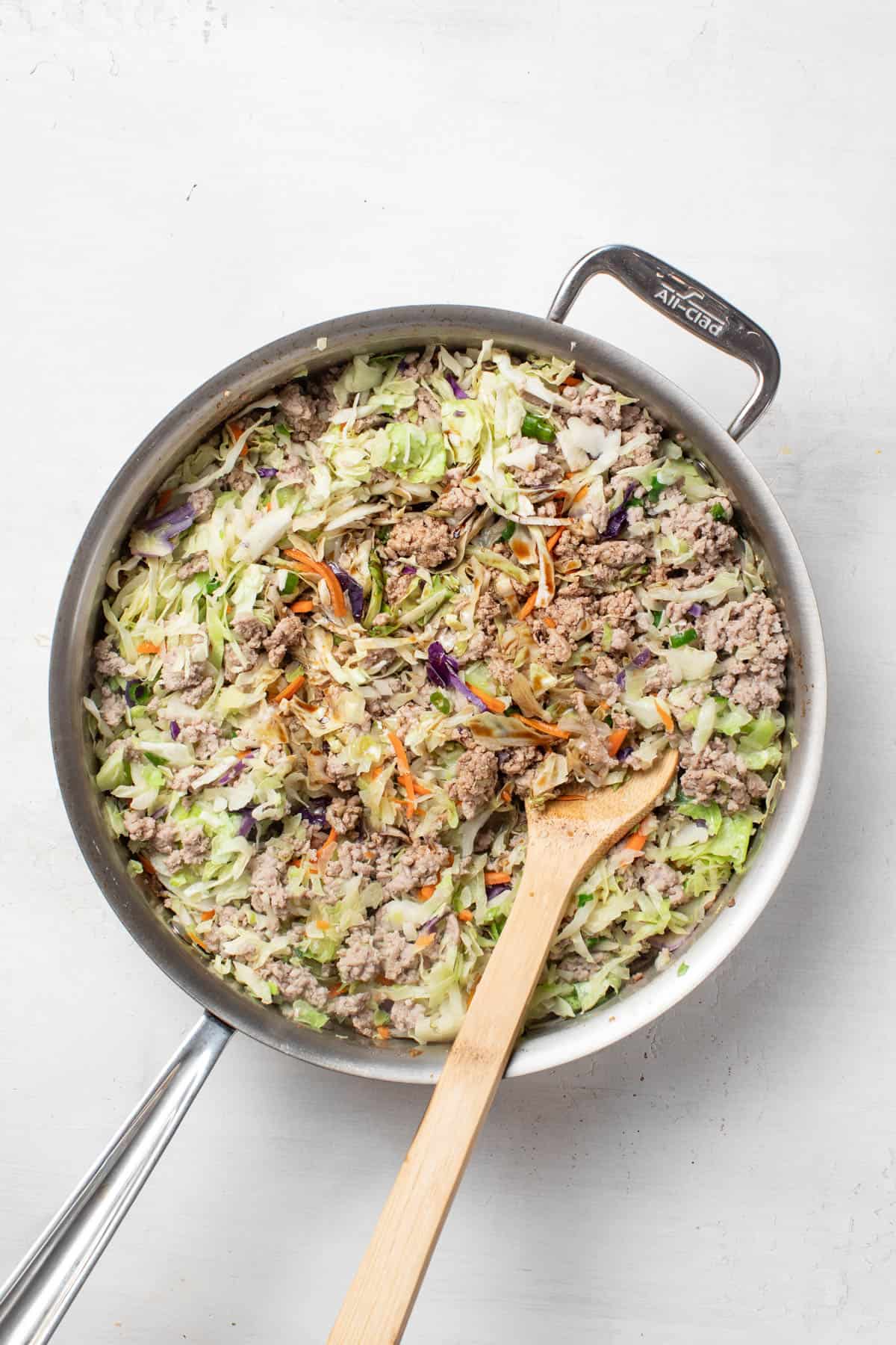 Stirring the coconut aminos into the turkey and slaw mixture.