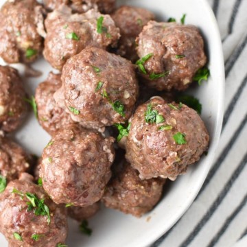 meatballs piled in a white bowl on a striped towel