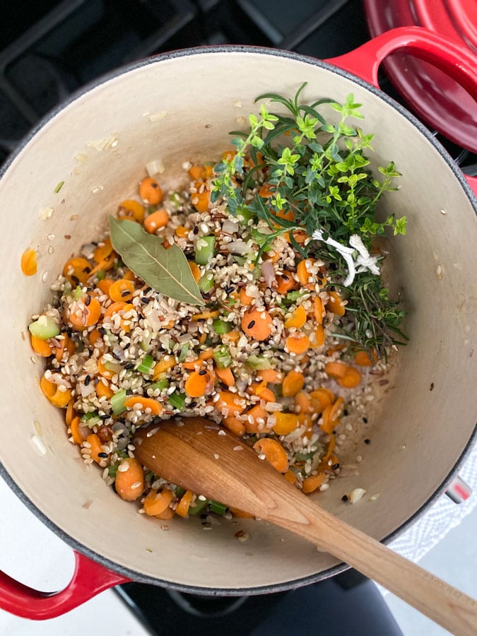 vegetables, herbs, and rice in a pot to make soup