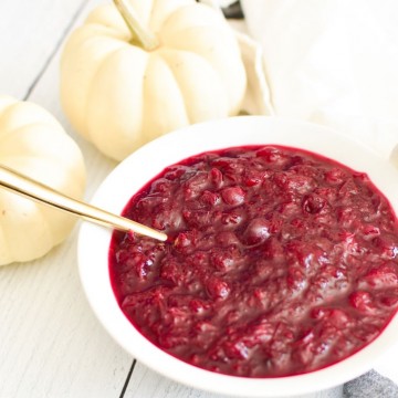 Cranberry sauce in a white bowl with white pumpkins in the background