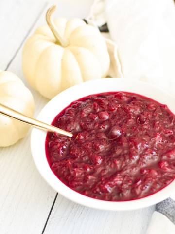 Cranberry sauce in a white bowl with white pumpkins in the background