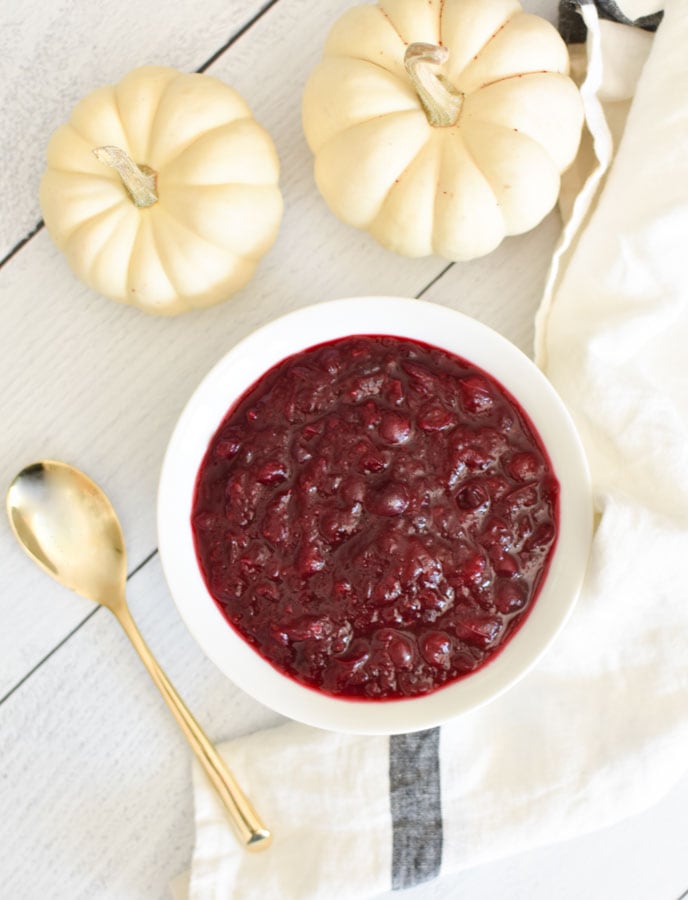 a bowl of cranberry sauce next to a gold spoon