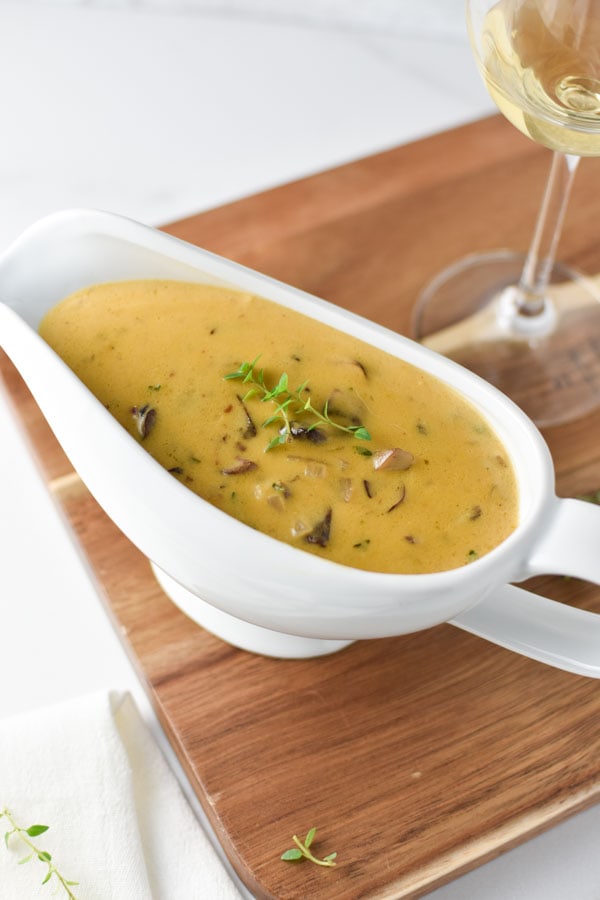 mushroom gravy in a white bowl on a wooden board