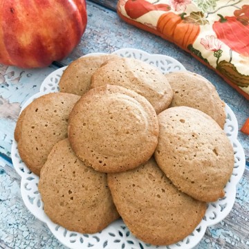 Stacked honey spice cookies on a white plate on a wooden board