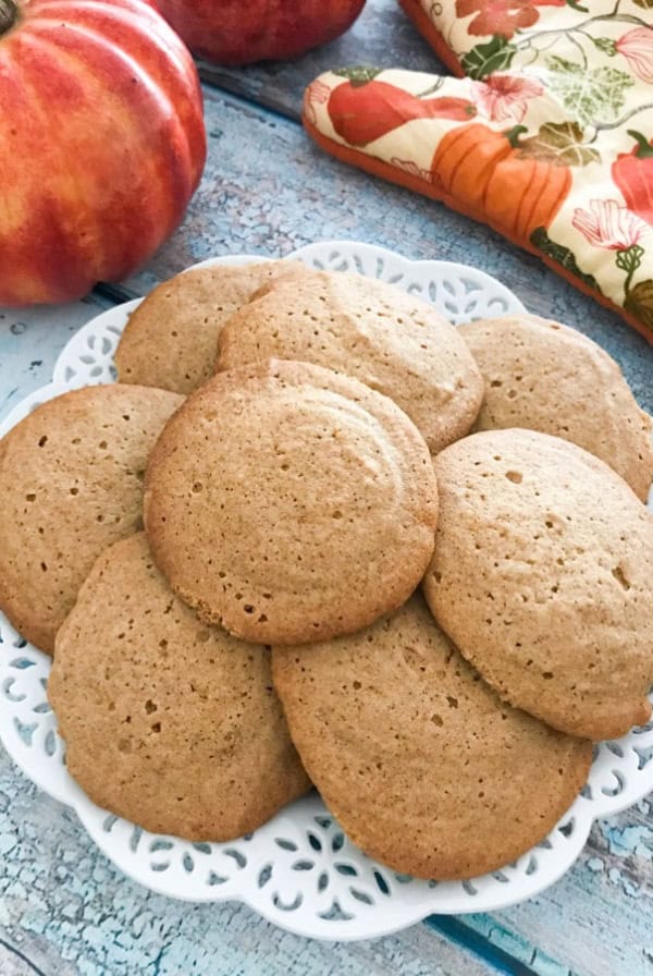 Stacked honey spice cookies on a white plate on a wooden board