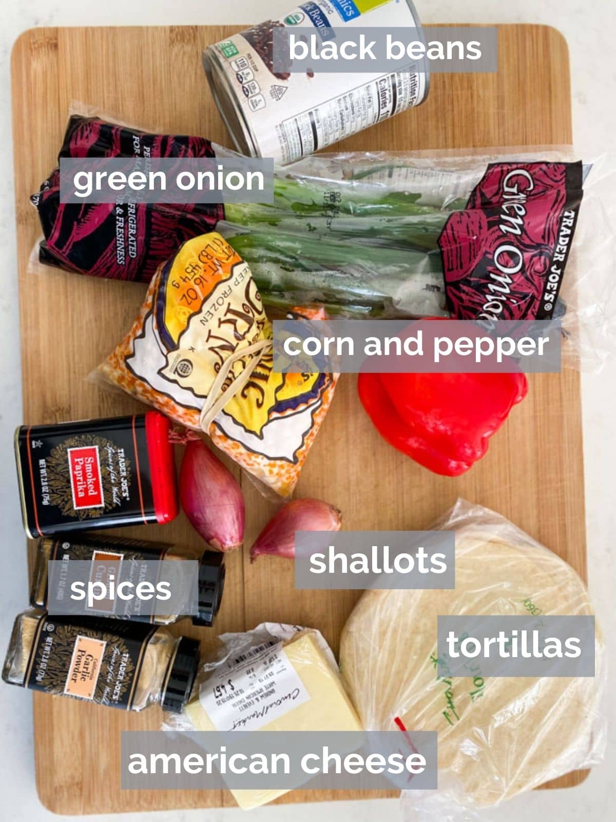 Spices, ground turkey, tortillas, pepper, corn and cheese on a cutting board.