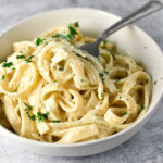 Boursin pasta topped with parsley tangled around a fork in a white bowl