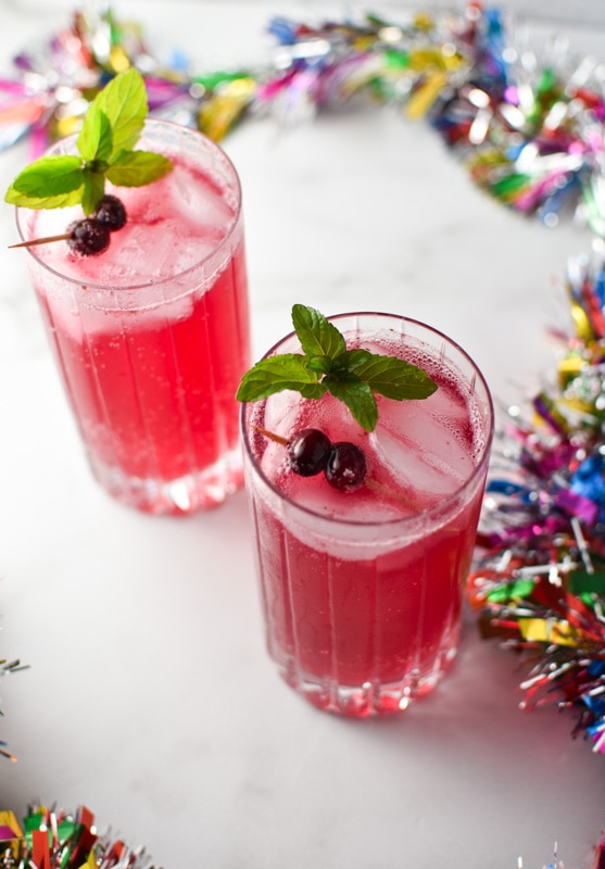 Cranberry mocktail garnished with mint and sugared cranberries with tinsel