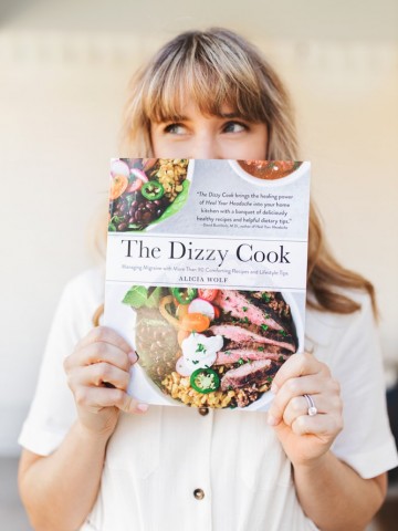 A girl holding The Dizzy Cook Cookbook in a white dress