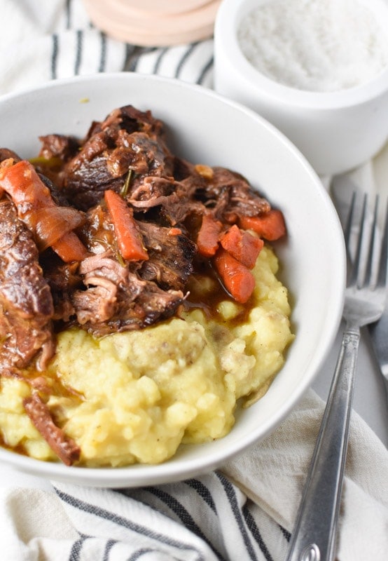 Pot roast in a white bowl with mashed potatoes and salt