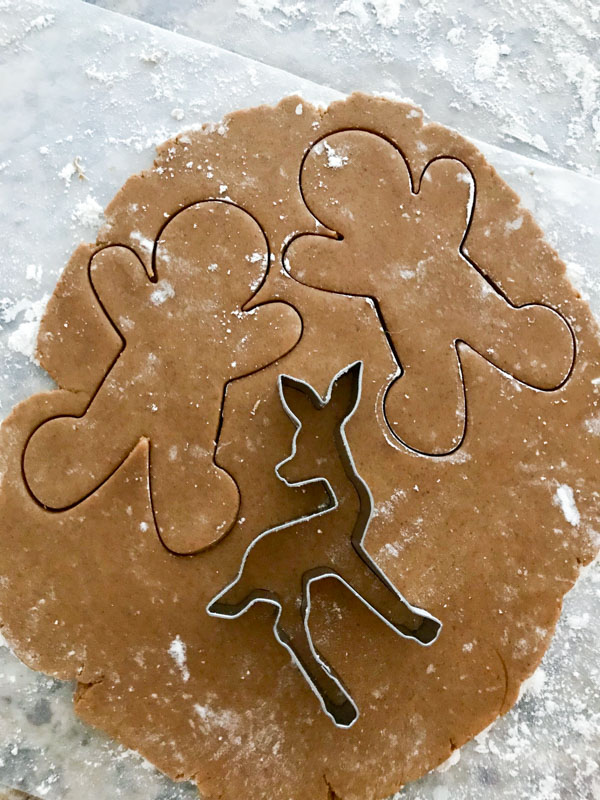 Rolled out gingerbread cookie dough with a deer cookie cutter on top, cutting out the shape