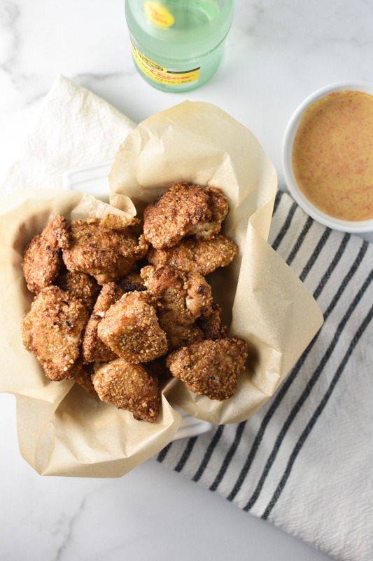 A pile of chicken nuggets next to a bowl of homemade honey mustard chick fil a sauce