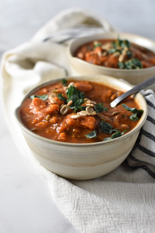 A bowl of curry sweet potato soup with a silver spoon