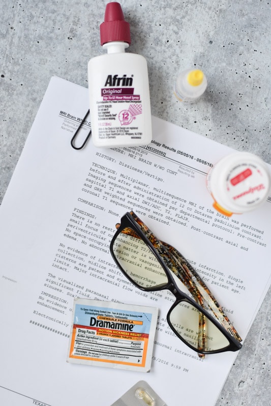 Afrin, migraine glasses, vertigo pills and a diagnosis paper on a table with dramamine