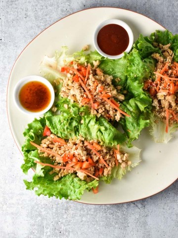 Lettuce wraps with chicken on a plate next to two dipping sauces