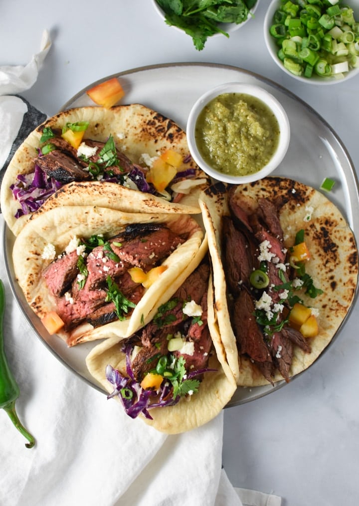 Steak tacos on a grey plate with salsa verde