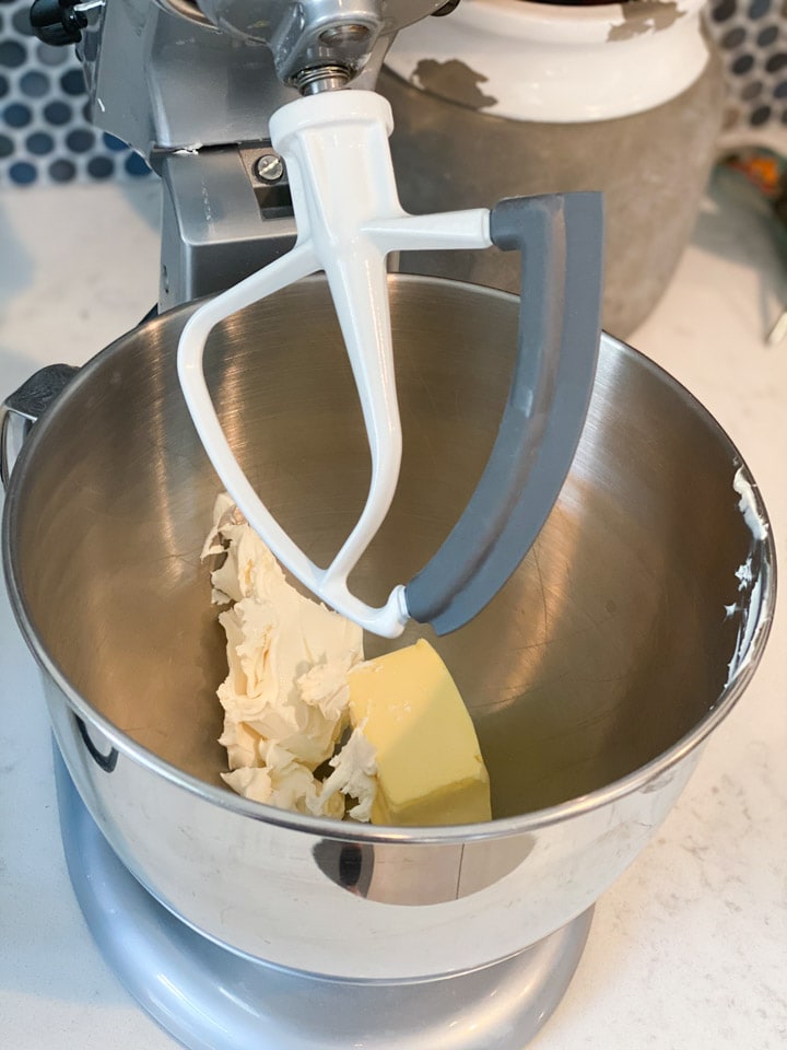 Cream cheese and butter in an electric mixer bowl.