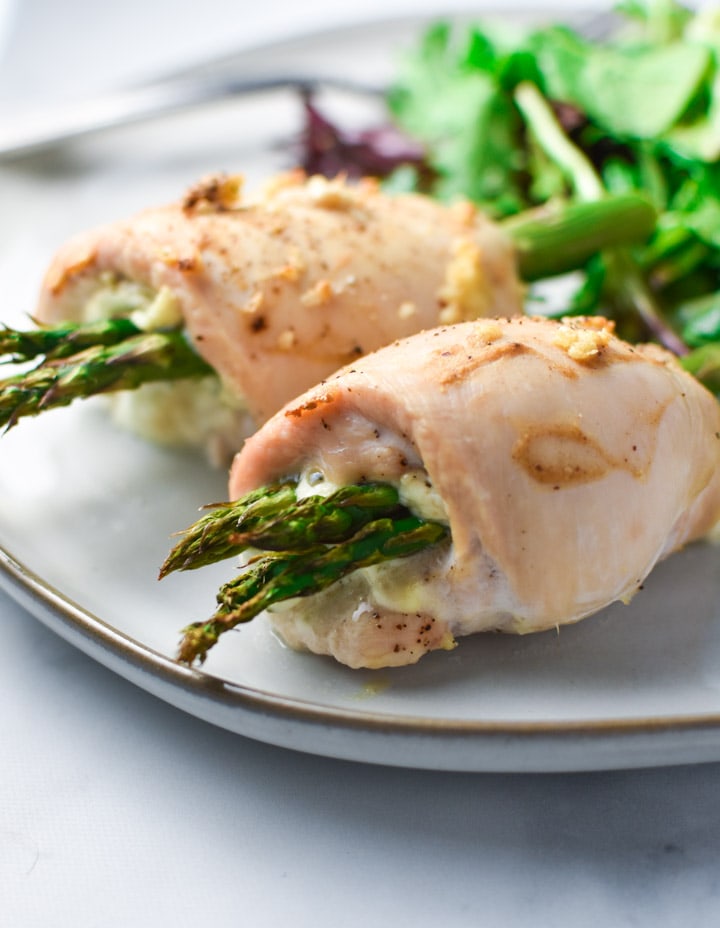 2 baked chicken breasts stuffed with boursin cheese and asparagus on a plate