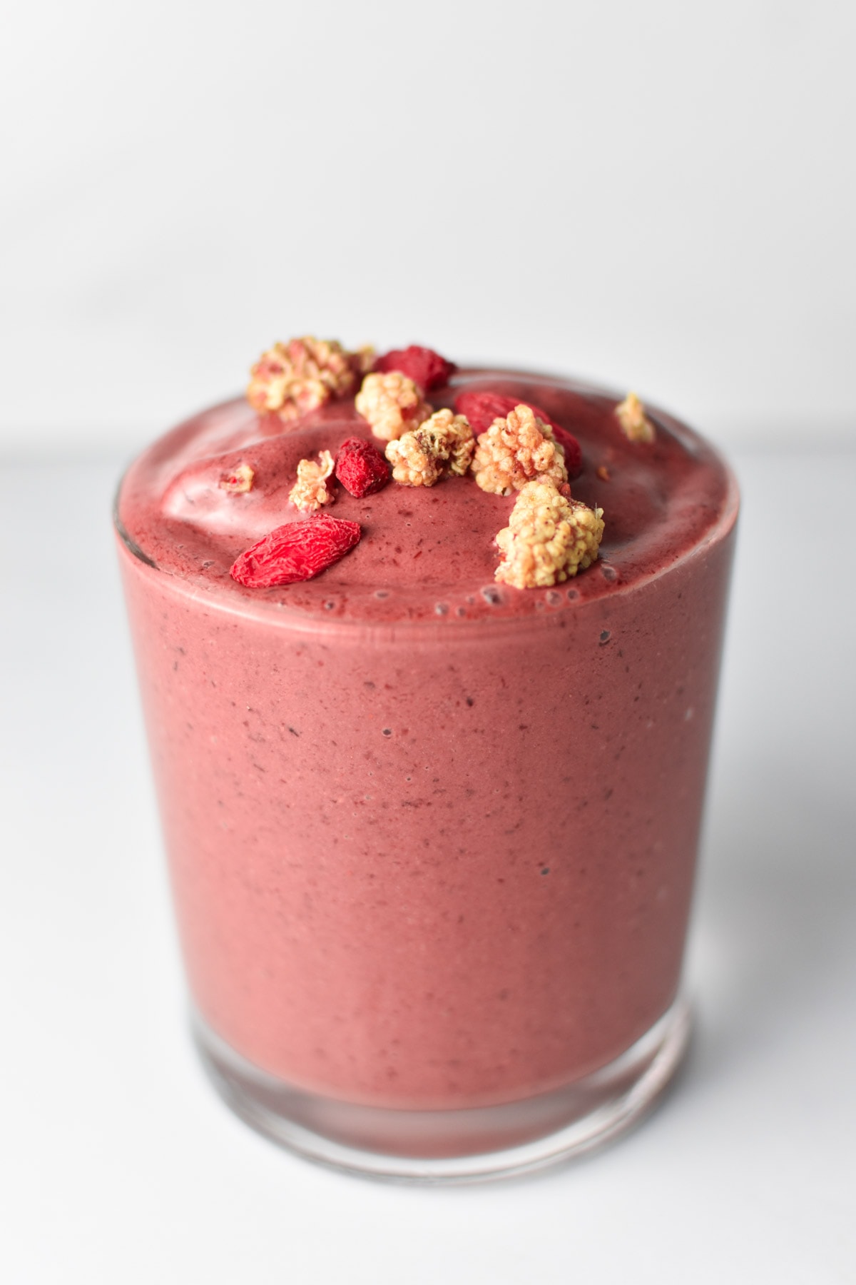 A fruit smoothie topped with goji berries on a table.