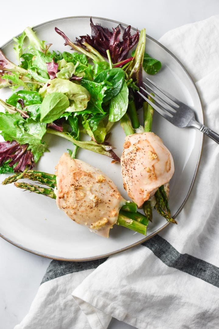 Two Boursin stuffed chicken breasts on a grey plate with salad and a fork