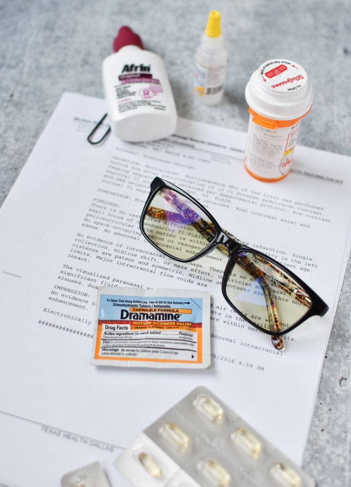 Pills, migraine glasses, afrin and eye drops scattered on a table