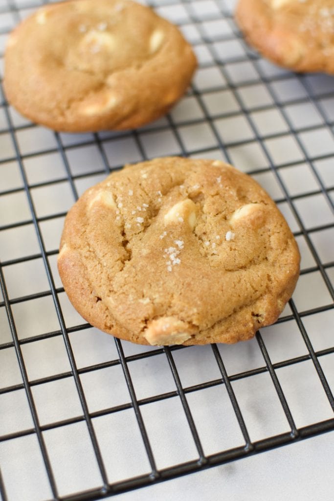 A white chocolate chip cookie on a baking rack