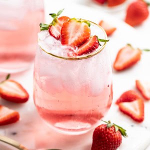 A strawberry mocktail with ice and fresh strawberries.