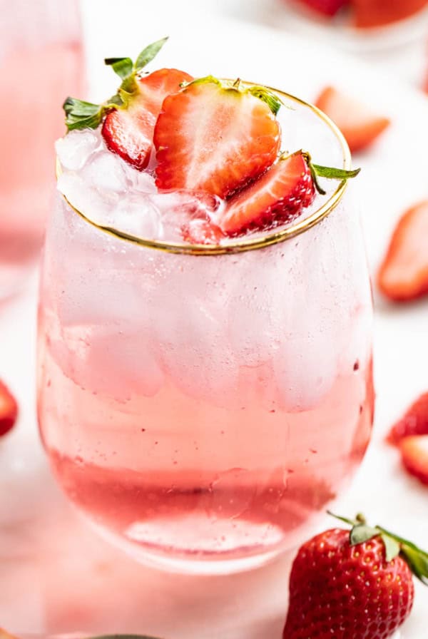 A strawberry mocktail with ice and fresh strawberries.