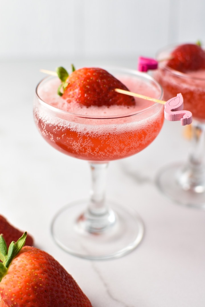 Two strawberry mocktails in coupe glasses with a strawberry on top