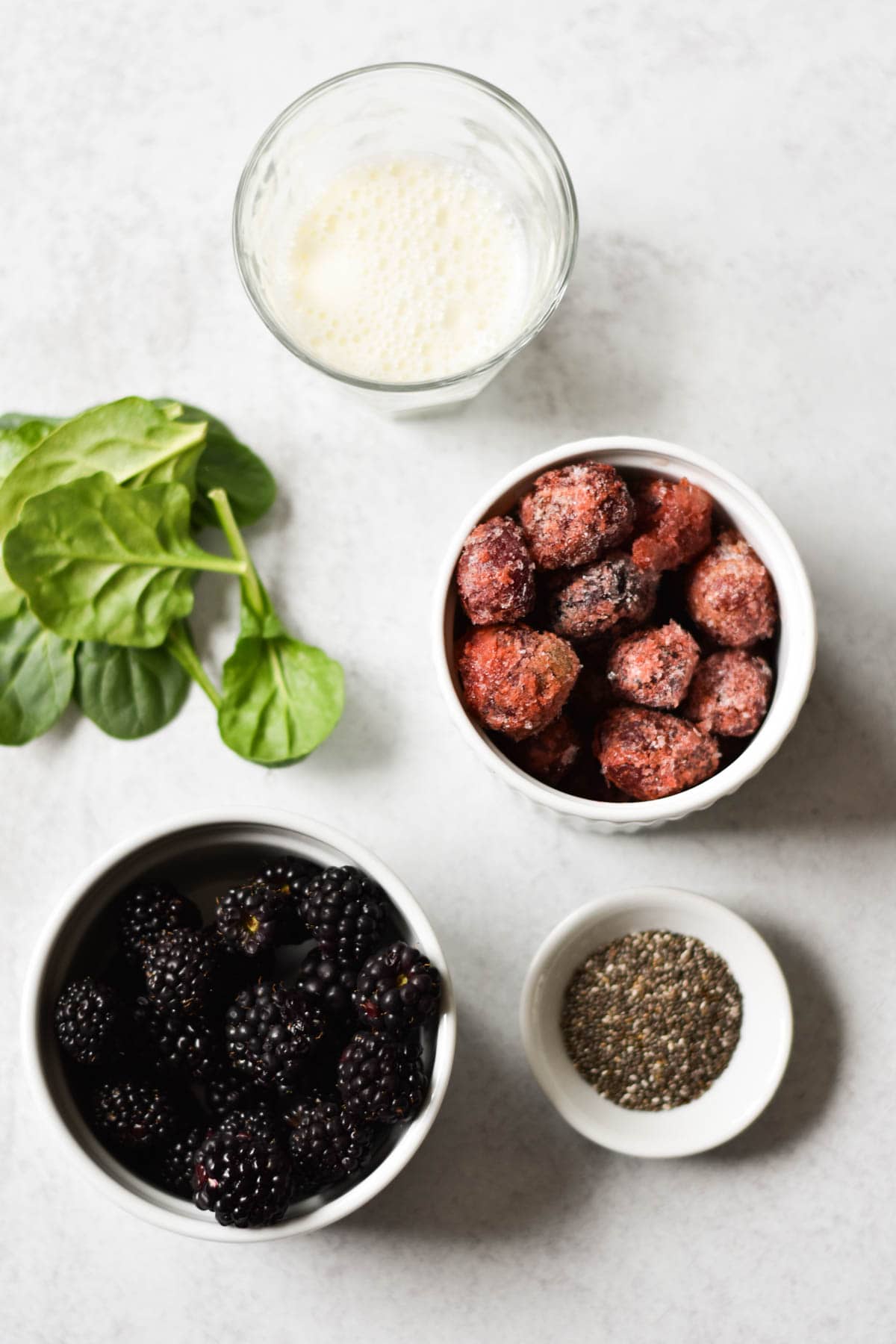 Blackberries, cherries, spinach, chia, and milk on a table. 