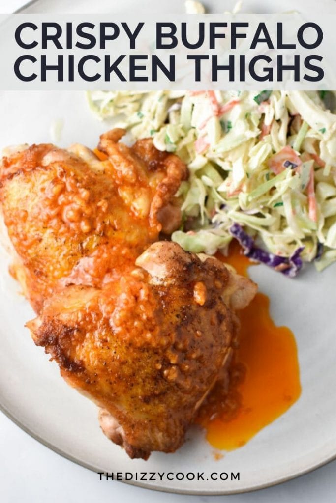 Two crispy buffalo chicken thighs on a plate with coleslaw