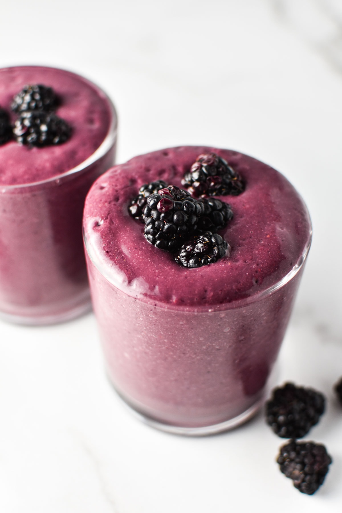 Two purple smoothies with blackberries on top. 