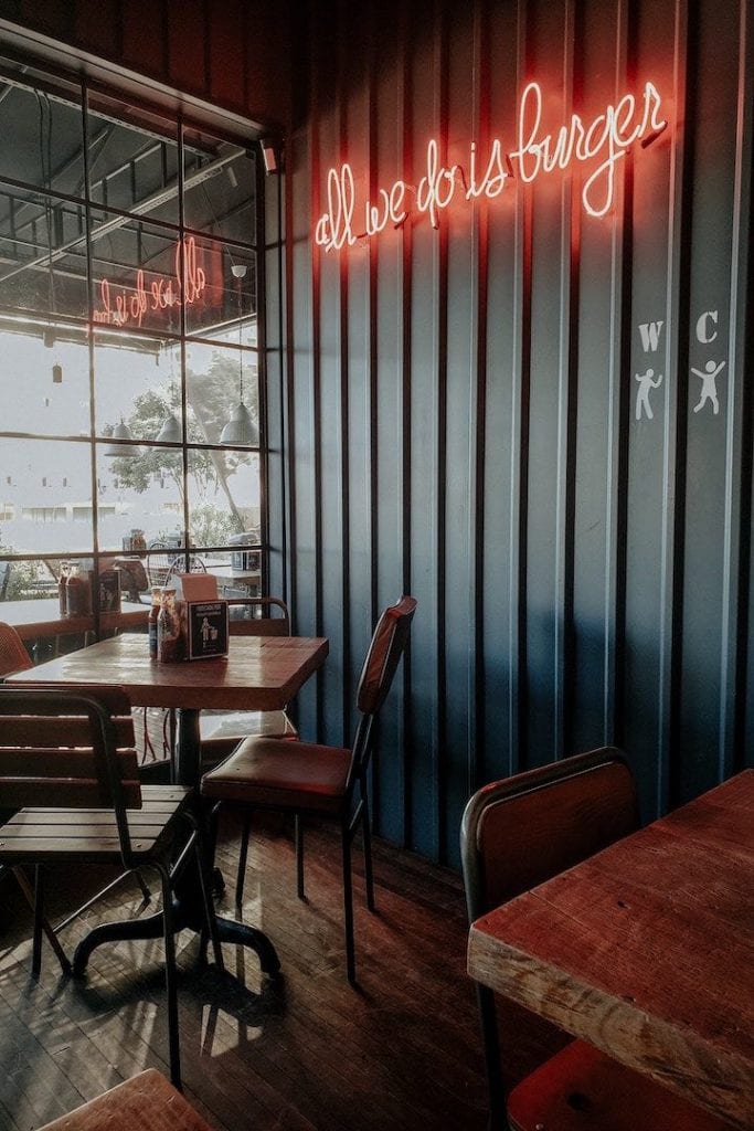 A photo of the inside of a restaurant with a sign for burgers in the background