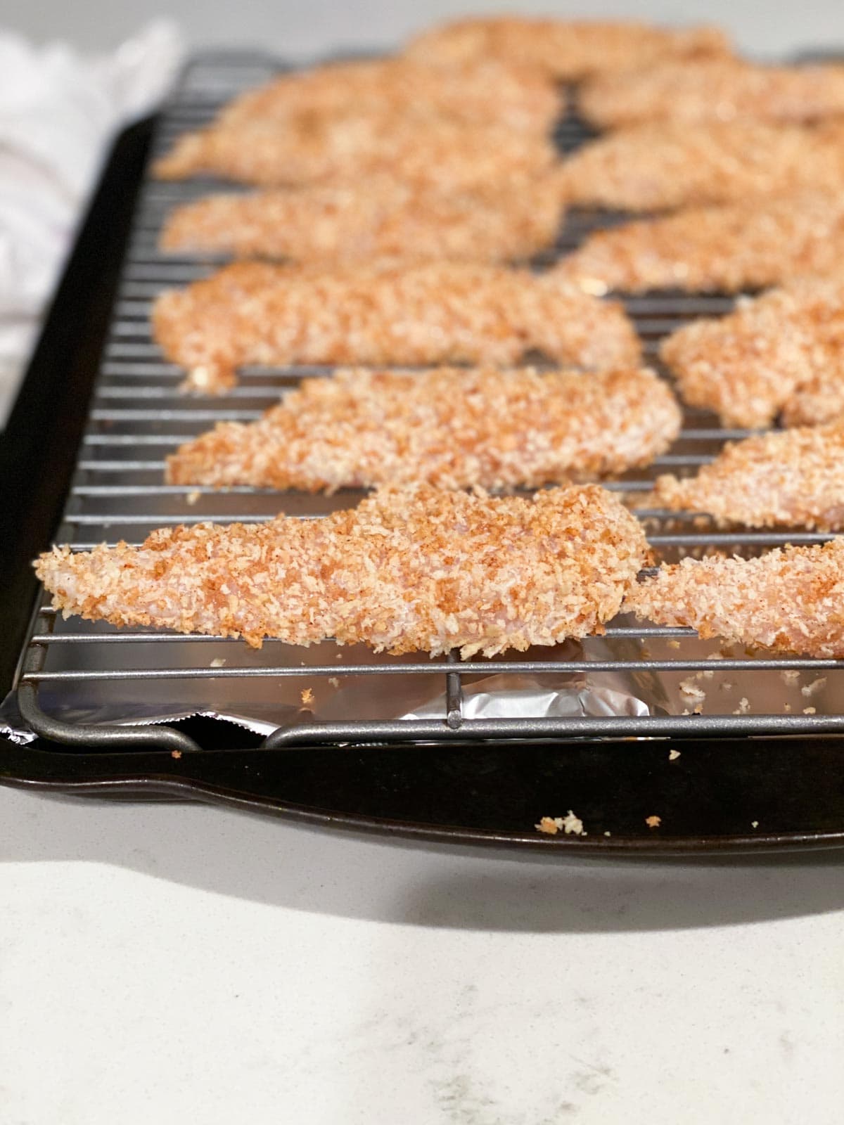 Chicken tenders lined up on a baking rack.