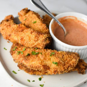 A plate full of instant pot air fryer chicken tenders next to a honey mustard sauce.