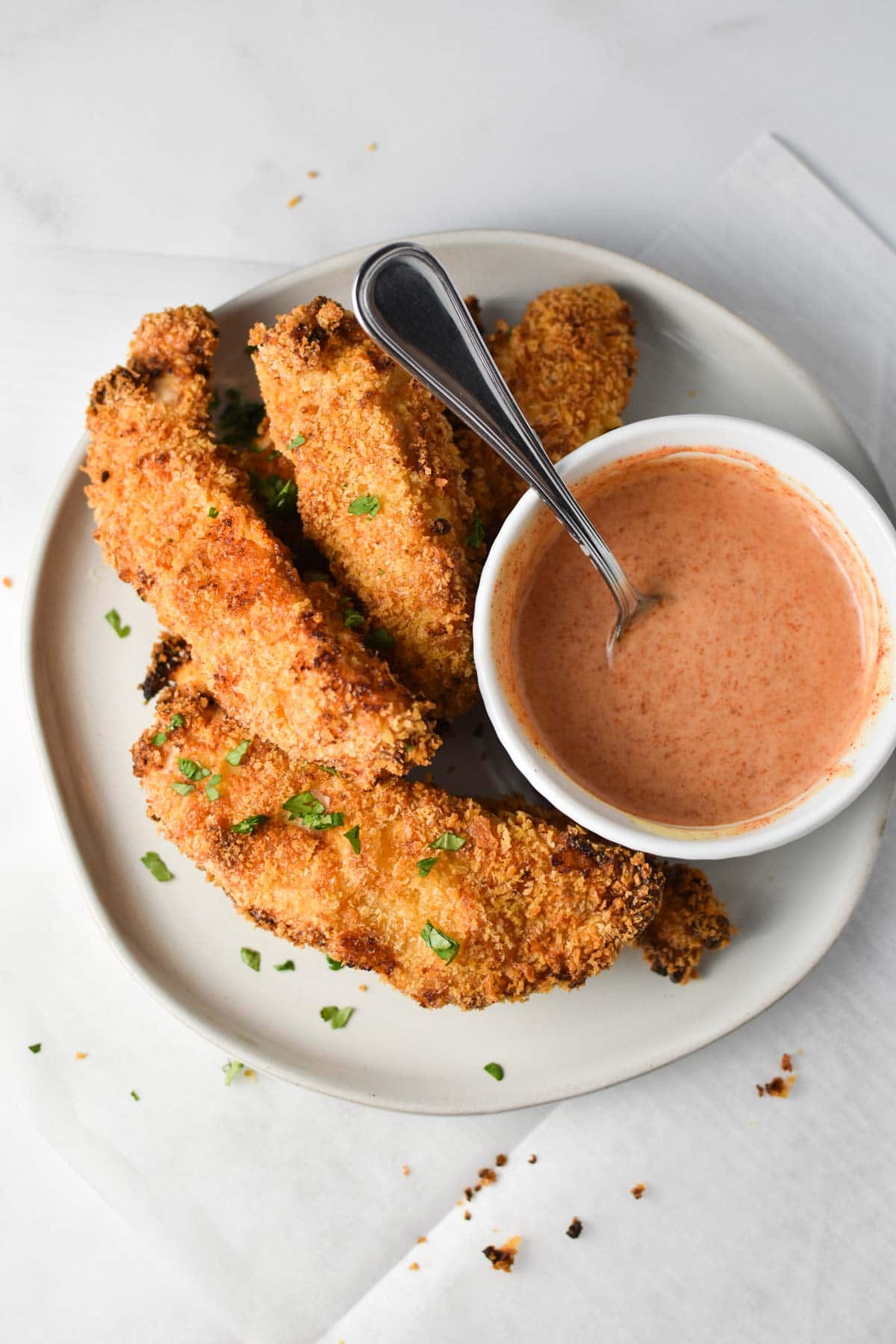 A plate full of instant pot air fryer chicken tenders next to a honey mustard sauce.